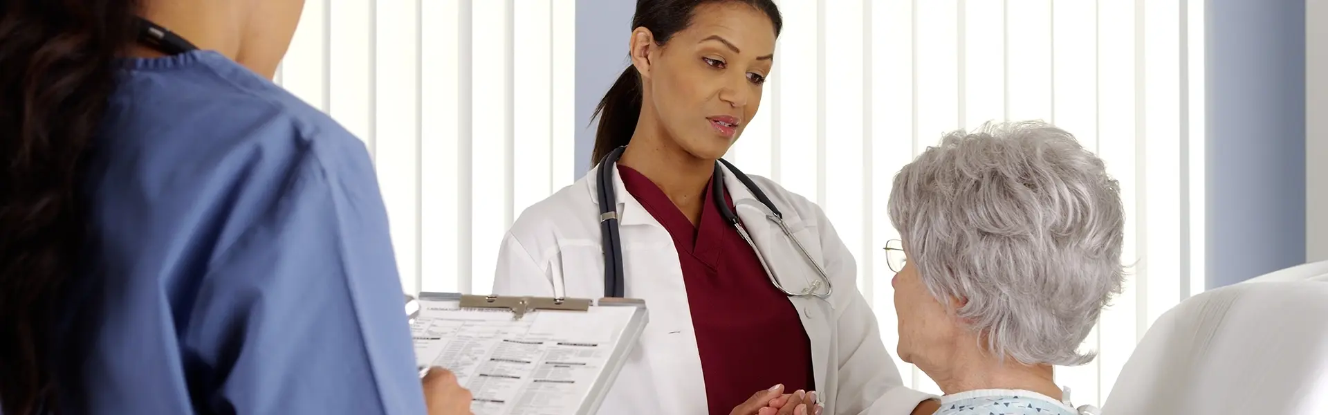 doctor and nurse talking to elderly patient