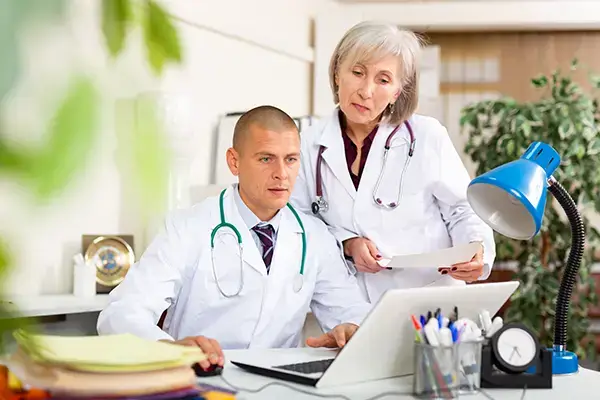 Male physician sitting at table in his office with his female colleague