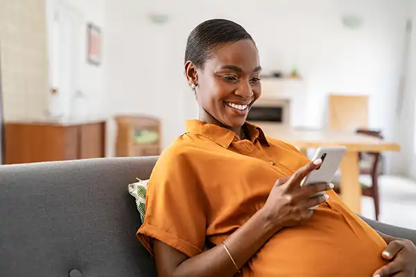 pregnant lady smiling while watching her phone