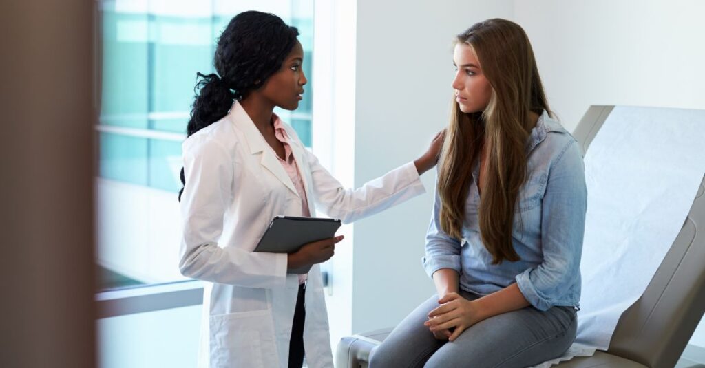 Doctor Talking To Unhappy Teenage Patient