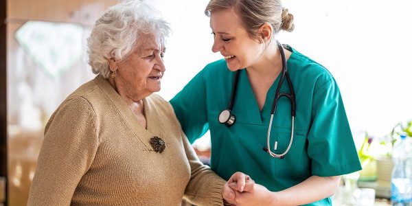 Friendly nurse supporting an elderly lady