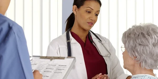 doctor and nurse talking to elderly patient