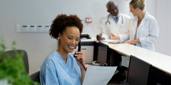 female-doctor-at-desk-in-hospital-reception-talking-on-phone